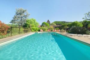 a swimming pool with blue water in a yard at Maison des papillons Daglan in Daglan