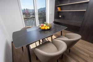 a dining room table with chairs and a bowl of fruit at Hotel Cube 55 - Business Suites in Skopje
