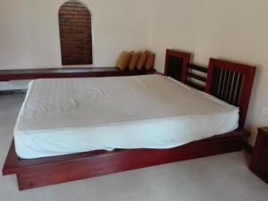 a bedroom with a wooden bed with white sheets at Maple Suite in Kadawata