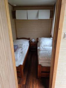 two twin beds in a small room with wooden floors at Domek letniskowy - niebieski całoroczny in Stegers
