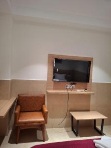a room with a chair and a tv and a table at Arunachal residency in Dibrugarh