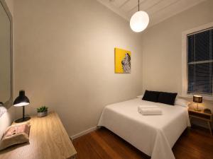 a bedroom with a white bed and a yellow painting at CitiRooms Auckland in Auckland