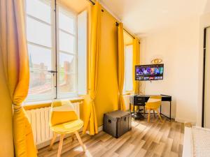 a room with yellow curtains and a desk and a television at Chic Bastide in Carcassonne
