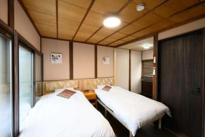two beds in a small room with wooden ceilings at NOW Onomichi in Onomichi