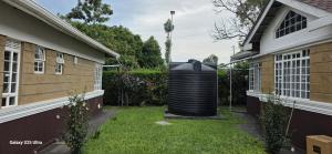 a large black trash can sitting in a yard next to a house at The Amanda Bed & Breakfast in Migori