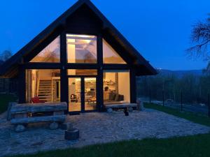 a small cabin with a large glass window on a field at Dom dwa światy in Międzybrodzie Bialskie