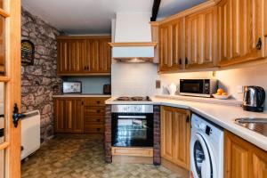 a kitchen with wooden cabinets and a stove top oven at Lupin Cottage in Wooler
