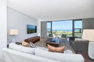 a living room with white furniture and a view of the ocean at Sonvanger Villa Struisbaai in Struisbaai