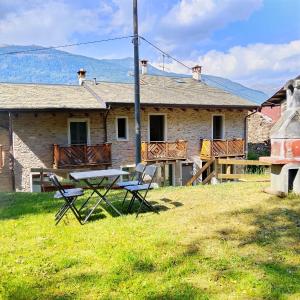 a house with a picnic table and chairs in the yard at Ca Poschiavini - Casa Lares in Casa Piali