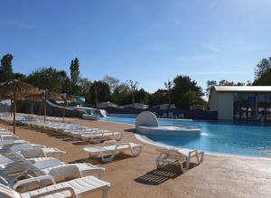 a pool with white lounge chairs and a swimming pool at ZEcamping 4 étoiles pet friendly terrain multisports piscine couverte in Angles