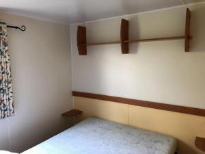 a small bedroom with a bed and shelves on the wall at ZEcamping 4 étoiles pet friendly terrain multisports piscine couverte in Angles
