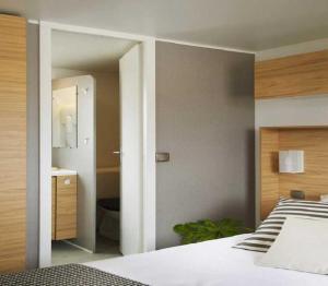 a bedroom with a white bed and a bathroom at ZEcamping familial espace aquatique pet friendly in Argelès-sur-Mer