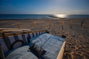 a bed on a beach with the ocean in the background at Schlafstrandkorb Nr 5 in Kellenhusen