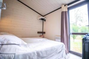 a bedroom with a bed and a window at ZEcamping 4 étoiles familial pet friendly animé piscine chauffée in Aramits +98 photos