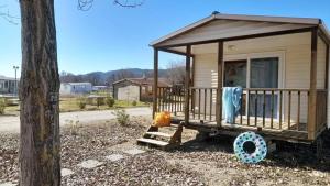 a tiny house with a porch and a tree at ZEcamping 3 étoiles chiens acceptés piscine bar et restaurant in Mézel