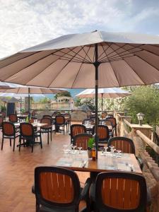 a patio with tables and chairs under an umbrella at ZEcamping 3 étoiles à 1km de la plage piscine jacuzzi animaux acceptés in Viggianello