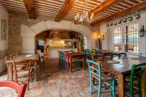 a restaurant with wooden tables and chairs and a kitchen at Mas Loisonville - 32 couchages in Grillon