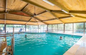 a swimming pool with people in the water at ZEcamping 4 pet friendly piscine couverte et parcours Fitness in Pressignac