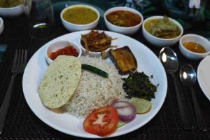 a plate of food with rice and vegetables and other foods at Rajbari Resort in Shānti Niketan