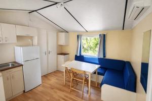 a small kitchen with a table and a blue couch at ZEcamping 3 étoiles familial avec Piscine et Bar-restaurant in Saint-Honoré-les-Bains