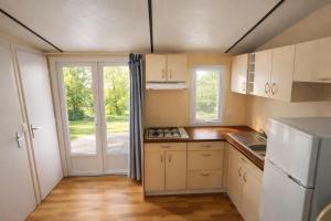 a small kitchen with white cabinets and a window at ZEcamping 3 étoiles familial avec Piscine et Bar-restaurant in Saint-Honoré-les-Bains