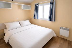 a bedroom with a white bed and a window at ZEcamping 3 étoiles familial avec Piscine et Bar-restaurant in Saint-Honoré-les-Bains +43 photos