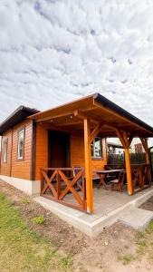 a wooden cabin with two picnic tables on a deck at Domek Agroturystyka Ładne Pole in Ładne Pole