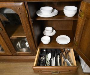 a wooden cabinet with white plates and bowls and utensils at NOW Onomichi in Onomichi