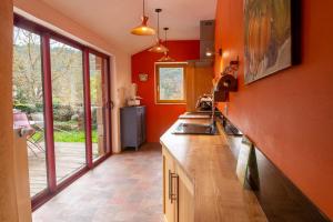 a kitchen with red walls and a counter with a sink at Chez mamiethé in Ispagnac