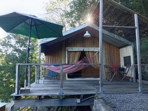 a hammock and an umbrella on a wooden deck at African Tent in Ponte da Barca