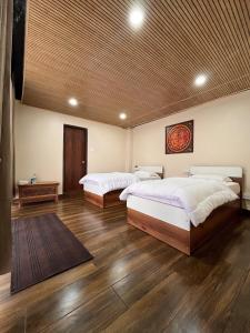 two beds in a large room with wooden floors at Zimba Cottage Retreat 2 in Kalimpong +2 photos