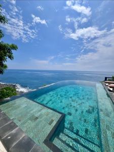 a swimming pool with a view of the ocean at Makawi Tuwa Cliff - Luxury Cliff Stay with Private Beach, Infinity Pools and Ocean View in Seraya