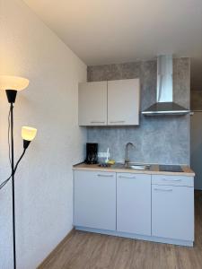 a kitchen with white cabinets and a sink at Stäy Gronau in Am Berge