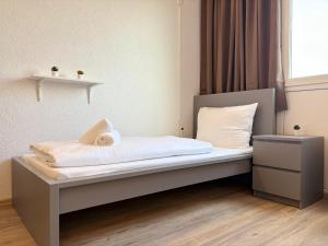 a small bedroom with a bed with white sheets at Stäy Gronau in Am Berge