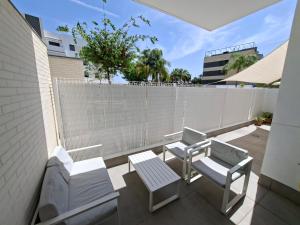 a balcony with two chairs and a table and a fence at Green Simon - Piso nuevo con Piscina 2024 in San Juan de Aznalfarache