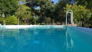a swimming pool with blue water and trees in the background at Agriturismo Boccadifuoco sul Fiume Alcantara in Motta Camastra