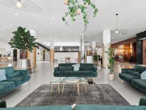a living room with green couches and tables at Novotel Paris Est Centre de Conférence in Bagnolet