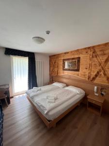 a bedroom with a large bed with a wooden wall at Hotel Garni Relax in Fai della Paganella