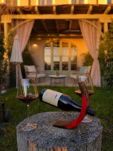 a bottle of wine and a glass on a stump at Langhe Wine & Relax in Novello