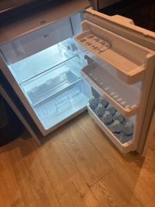 an empty refrigerator with its door open on a wooden floor at The Parade, Market Square room 3 in Northampton