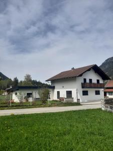 ein weißes Haus mit einem grünen Feld neben einer Straße in der Unterkunft Bleispitze Panorama in Bichlbach