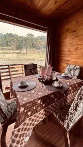 a table and chairs in a room with a window at Chalé do Lago - Refúgio Arara Azul in Urubici