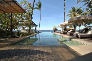 a swimming pool at a resort with a view of the ocean at Villa Pantai Matanai in Tianyar