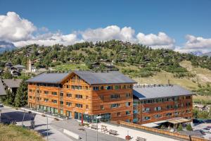 a large wooden building with a mountain in the background at Vercorin group lodge 18 people in Chalais