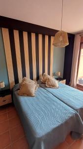 a bedroom with a blue bed with two pillows on it at El Mirador de Adrial in Ladrillar