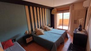a bedroom with a blue bed and a window at El Mirador de Adrial in Ladrillar