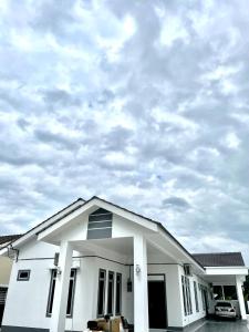 a white house with a cloudy sky in the background at dayah homestay in Siputih