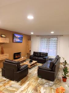 a living room with leather furniture and a flat screen tv at Caesars HOUSE Lac Belis in Luna de Sus