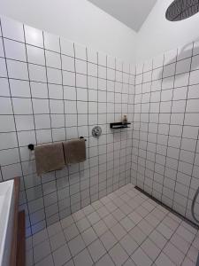 a white tiled bathroom with a shower and a towel at Gastenverblijf spoarsicht in Lioessens