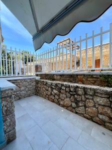 a patio with a stone wall and a fence at Beach Studio Apartment in Dhërmi